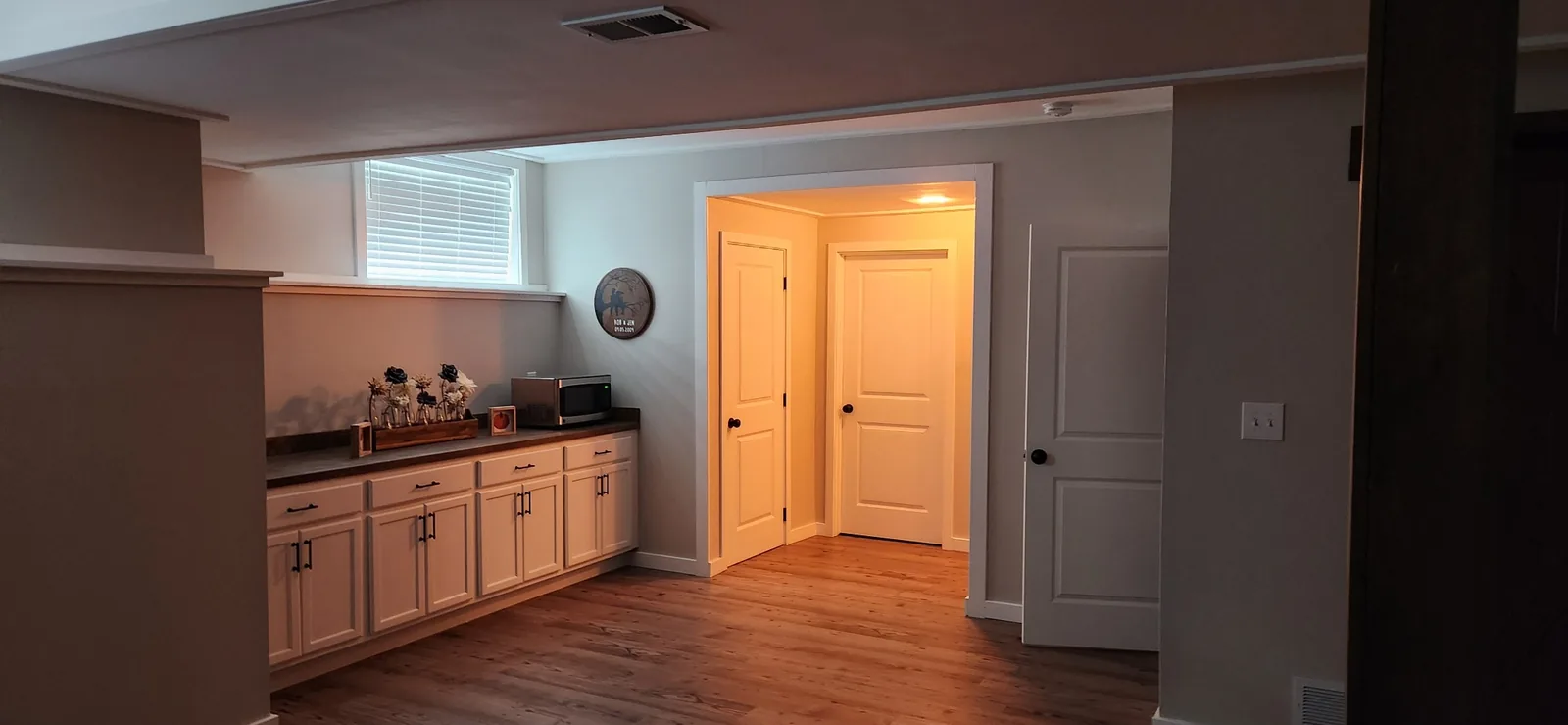 Finished basement kitchenette with white cabinetry and stained countertop